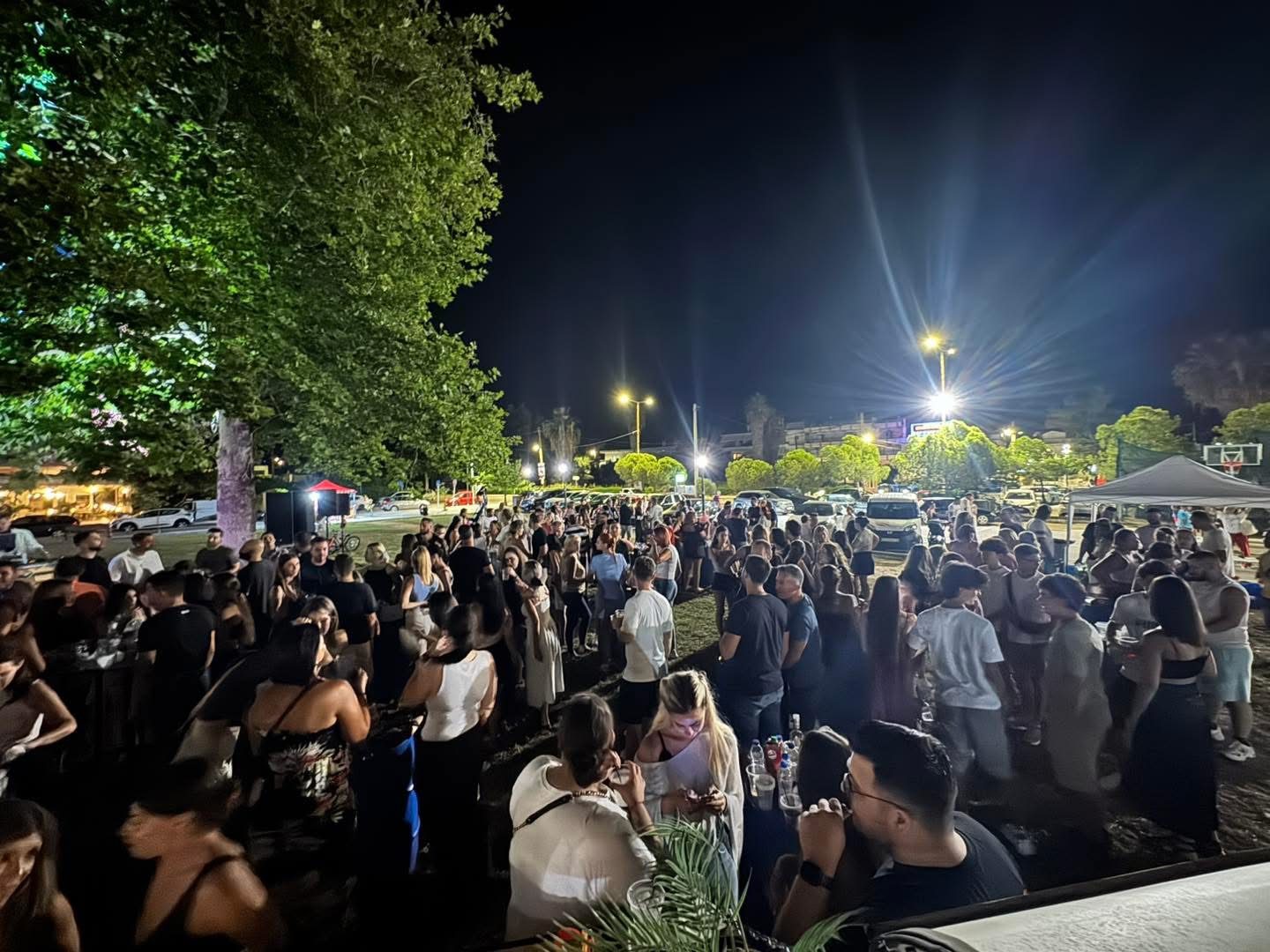 Πάρτι νεολαίας με πολύ κόσμο κάτω από τα δέντρα τη νύχτα