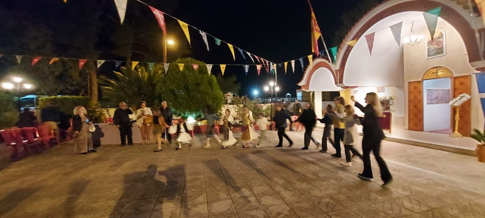 Χορευτική συνάντηση με παραδοσιακές φορεσιές στη νύχτα, μπροστά σε εκκλησία